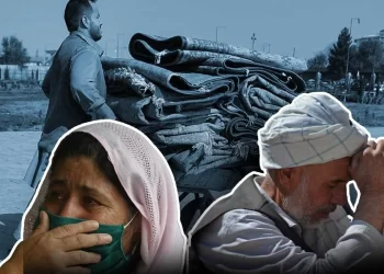 A grieving woman and man mourn as a vendor carries carpets through a Kabul street, reflecting the emotional and financial toll of mourning customs in Afghanistan. (Photo credit: AFP)