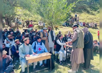 A crowd gathers around an ICRC worker during the distribution of post-harvest equipment to farmers in Panjshir. (Photo credit: @ICRC_af)