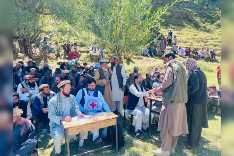A crowd gathers around an ICRC worker during the distribution of post-harvest equipment to farmers in Panjshir. (Photo credit: @ICRC_af)