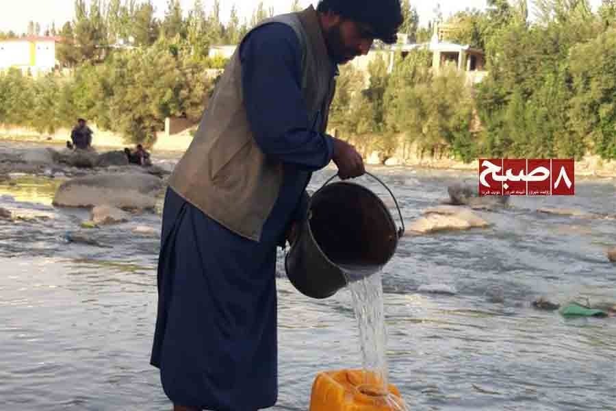 A Jogi man fills a container with river water near a settlement in Badakhshan. (Photo credit: 8am.media)