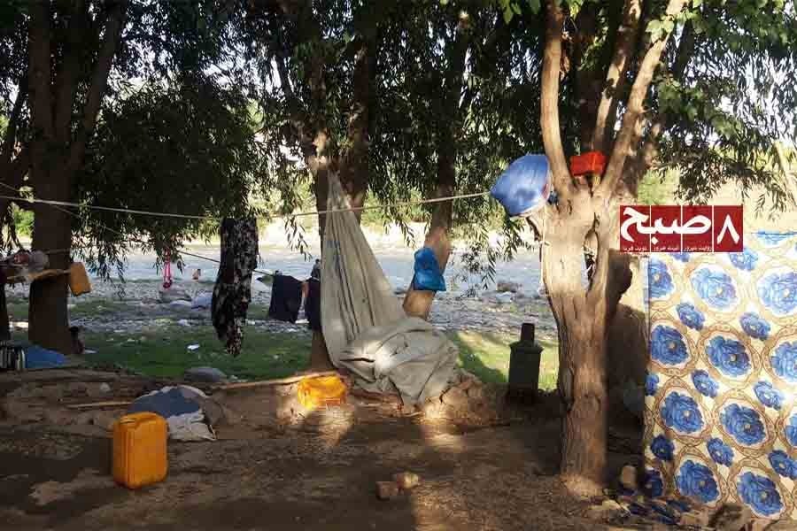 A makeshift camp with hanging bedding and water containers sits along a riverbank near a Jogi settlement. (Photo credit: 8am.media)