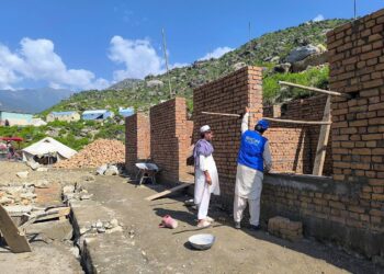 An IOM worker and a local resident take part in rebuilding homes for families affected by the earthquake in Kunar. (Photo credit: IOM)