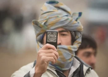 A man in a Nuristani cap holds up his phone amid growing complaints over Afghanistan's 10 percent telecom tax. (Photo credit: Reuters)
