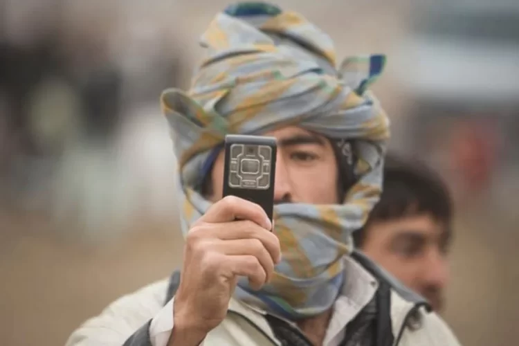 A man in a Nuristani cap holds up his phone amid growing complaints over Afghanistan's 10 percent telecom tax. (Photo credit: Reuters)