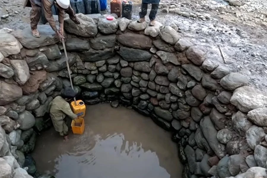 A man collects murky, sediment-filled water from a stone-lined well in a drought-stricken Afghan village. (Photo credit: Our Village)