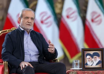 Iranian President Masoud Pezeshkian sits beneath portraits of Iran's supreme leaders alongside the Iranian flag. (Photo credit: - / IRANIAN PRESIDENCY / AFP)
