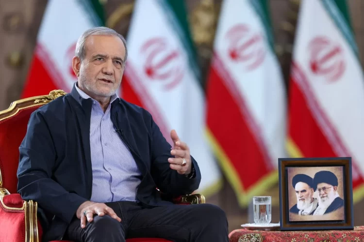 Iranian President Masoud Pezeshkian sits beneath portraits of Iran's supreme leaders alongside the Iranian flag. (Photo credit: - / IRANIAN PRESIDENCY / AFP)