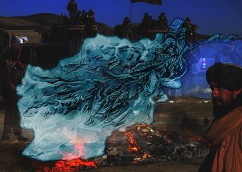 A Taliban fighter stands near a burning fire beside a map of Afghanistan, symbolizing the country's transformation under Taliban rule. (Photo credit: AFP)
