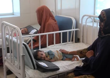 Two mothers sit beside their children, receiving treatment at a health facility in Afghanistan. (Photo: WHO)