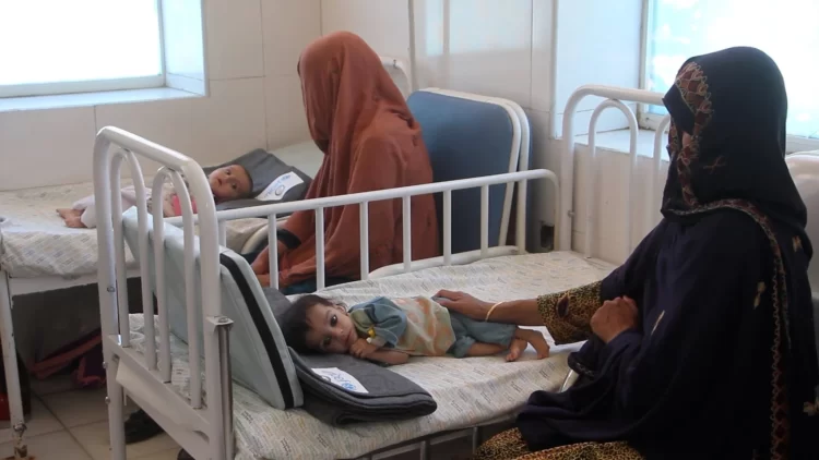 Two mothers sit beside their children, receiving treatment at a health facility in Afghanistan. (Photo: WHO)