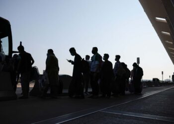 Migrants line up in front of a vehicle in the evening as they leave their homes in search of safety. (Photo credit: Anna Moneymaker/Getty Images)