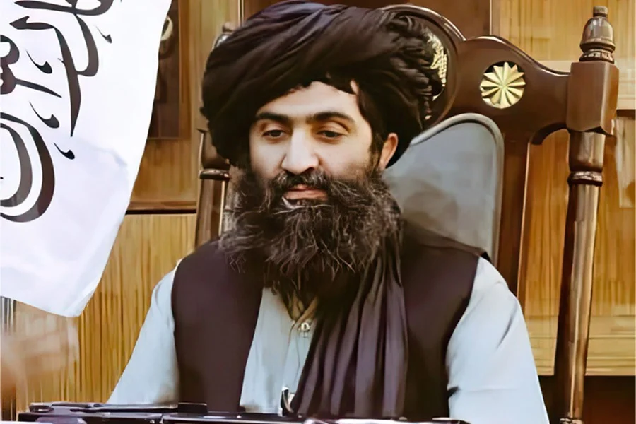 Abdul Ahad Haji Talib, head of Hibatullah Akhundzada's security guards and commander of the Hibati Unit, sits in a wooden chair beside a white flag. (Photo credit: 8am.media)