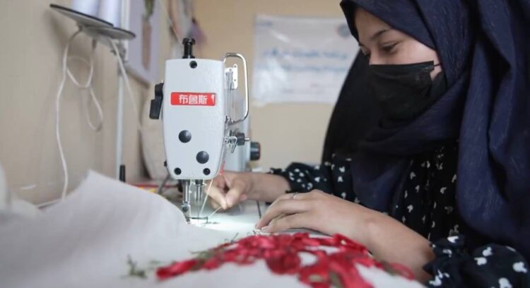 A woman in a hijab works with a sewing machine during technical skills training in Afghanistan. (Photo credit: UNICEF)