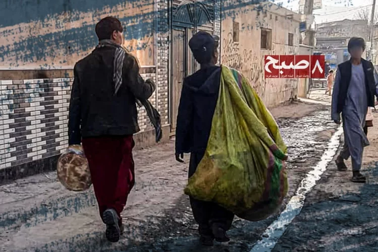 Two boys walk along a muddy street, one carrying a large sack on his back, as children in Afghanistan take on work to support their families. (Photo credit: 8am.media)