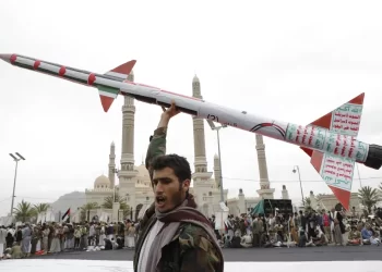 A Houthi supporter holds a model missile during a gathering in Yemen, with a mosque visible in the background (Photo: AP)