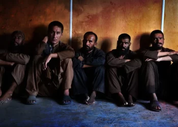 Men sit against a wall inside a drug treatment center in Kandahar, where patients and families allege narcotics are sold to those seeking recovery. (Photo credit: AFP)