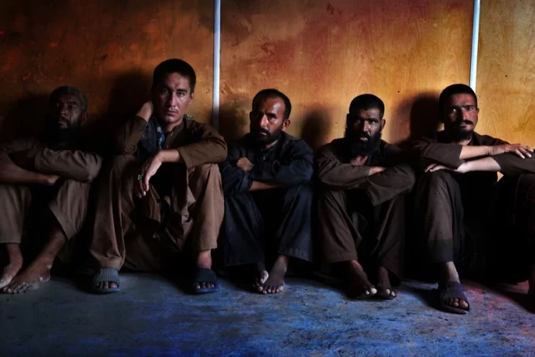 Men sit against a wall inside a drug treatment center in Kandahar, where patients and families allege narcotics are sold to those seeking recovery. (Photo credit: AFP)