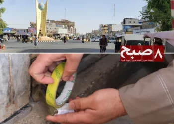 A Taliban municipality official seals a shop in Kandahar city as traders complain of high taxes and licence fees, with a busy city roundabout seen above. (Photo credit: 8am.media)