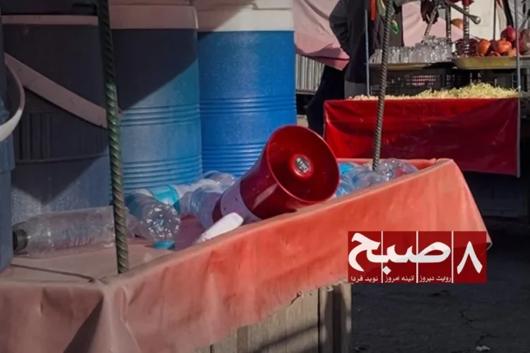 A loudspeaker used by a cart vendor sits among stacked bottles at a roadside stall in Kabul amid rising complaints of noise pollution. (Photo credit: 8am.media)