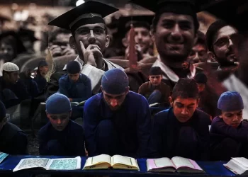 Young Afghan students in blue attire study religious texts at a madrasa, symbolizing the Taliban's push to replace India-educated technocrats with seminary-trained cadres. (Photo credit: Foad Ashtari + Reuters)