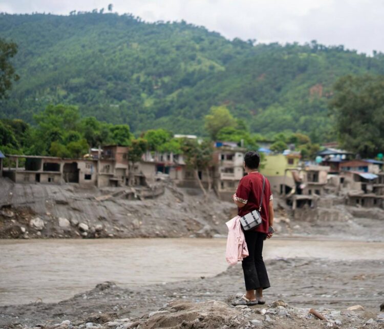 A person stands before floodwaters amid the destruction caused by deadly floods in Nepal. (Photo: UN WOMEN Nepal)