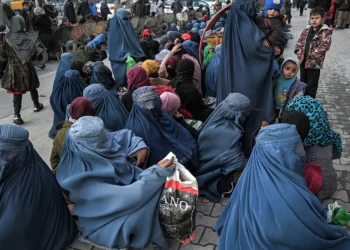 Women and children sit along a street in Afghanistan as people gather nearby (Photo: Afghanistan Analysts Network)