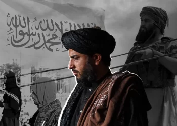 Armed Taliban members stand beneath the Taliban flag amid tensions over US-Taliban relations. (Photo credit: AFP)