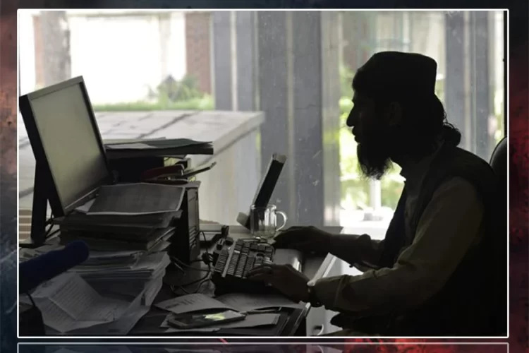 A silhouetted man works at a computer beside stacks of files in a government office under Taliban control. (Photo credit: AFP)