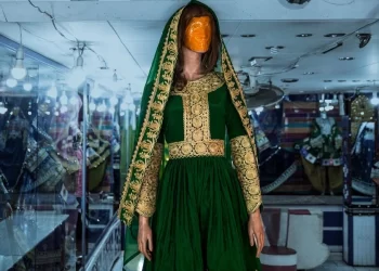 A traditional embroidered green dress is displayed on a mannequin at a handicraft shop, reflecting Afghanistan's declining handicraft sales market. (Photo credit: AFP)