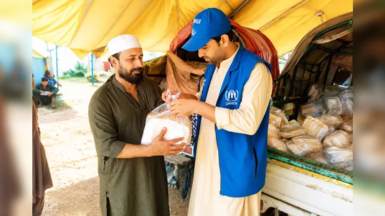 An UNHCR worker hands a hot meal to an elderly Afghan returnee at the Torkham border crossing (Photo: UNHCR)