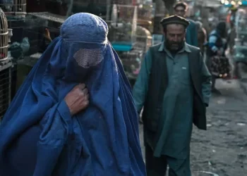 A woman wearing a chador walks ahead, followed by a man wearing traditional Afghan clothing. (Photo: AFP)