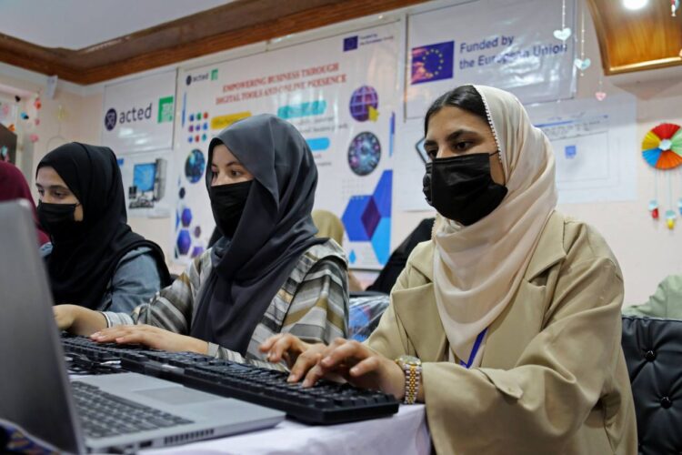 Girls work at computers in an office as restrictions on women’s access to UN offices in Afghanistan enter their second year. (Photo credit: UNDP)