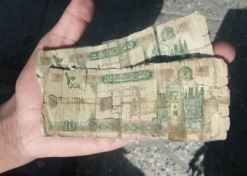 A resident of Kabul holds a stack of worn and torn Afghani banknotes still in circulation. (Photo credit: Social Media)