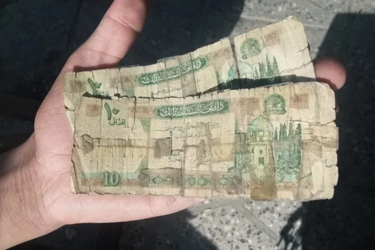 A resident of Kabul holds a stack of worn and torn Afghani banknotes still in circulation. (Photo credit: Social Media)