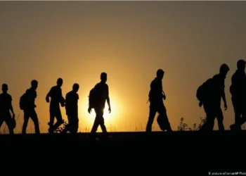 Afghan refugees walk along a road carrying their belongings as they travel at sunset