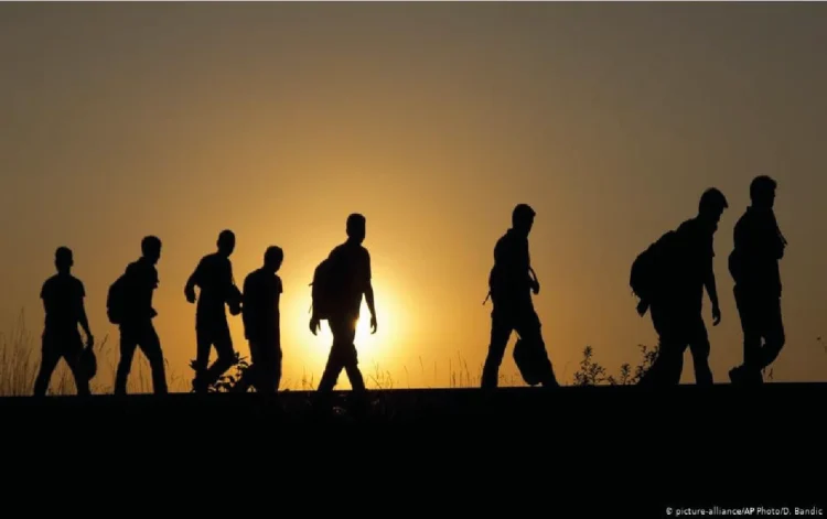 Afghan refugees walk along a road carrying their belongings as they travel at sunset