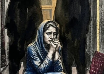 A young woman in a blue headscarf sits in a dim room with her hands clasped to her face, tears on her cheek, as psychologists warn of family pressure on girls. (Photo credit: AI)