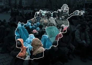 Women and children sit on a street in Afghanistan amid poverty and a deepening humanitarian crisis, with a map of the country outlined over the scene. (Photo credit: AFP)