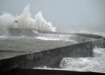 Powerful waves crash against a coastal breakwater during stormy weather, sending water high into the air (Photo: AFP)