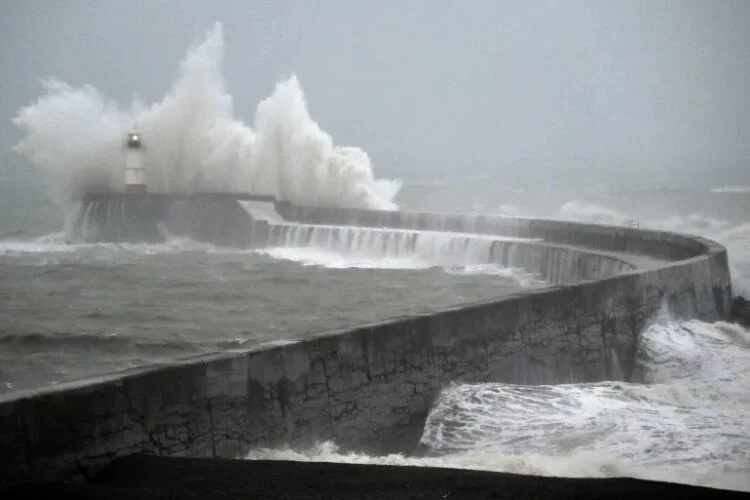 Powerful waves crash against a coastal breakwater during stormy weather, sending water high into the air (Photo: AFP)