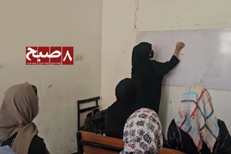 A female teacher writes on a whiteboard as students sit in a crowded classroom amid complaints over low salaries. (Photo credit: 8am.media)