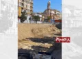 An excavation site for the underground market project in Ghazni city, with mounds of soil piled near commercial buildings and a mosque in the background. (Photo credit: 8am.media)