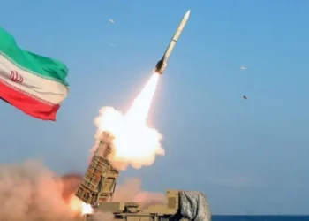 A missile is launched with the Iranian flag visible in the background amid escalating tensions between Iran, the United States and Israel. (Photo credit: Reuters)