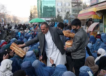 Men distribute bread to a large crowd of Afghan women and children gathered for food assistance in Kabul (Photo: REUTERS/Ali Khara)