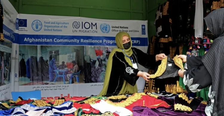 An Afghan woman displays traditional handmade clothing at an exhibition supported by the United Nations in Afghanistan (Photo: @UNDPaf)