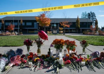 Flowers, candles, and stuffed animals placed outside a building behind police tape in memory of victims of a shooting in the United States (Photo: AP)