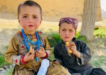 Two children eat biscuits while looking at the camera (Photo: WFP)