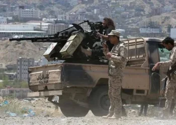 Yemeni fighters stand beside a pickup truck mounted with a heavy weapon in a mountainous urban area (Photo: Anadolu Ajansi)