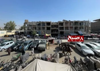 A view of a busy street in Kandahar, Afghanistan, showing vehicles, pedestrians, and commercial buildings