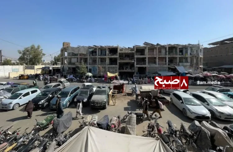 A view of a busy street in Kandahar, Afghanistan, showing vehicles, pedestrians, and commercial buildings